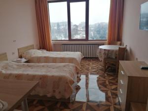 RazgradApart Hotel Central Razgrad的客房设有两张床、一张桌子和一扇窗户。