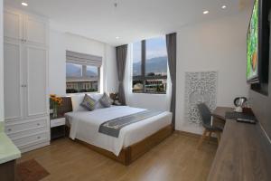 芽庄Skylight Hotel Nha Trang的一间卧室配有一张床、一张书桌和一个窗户。