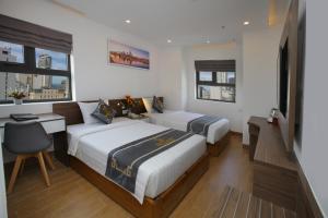 芽庄Skylight Hotel Nha Trang的一间卧室配有两张床、一张桌子和两个窗户。