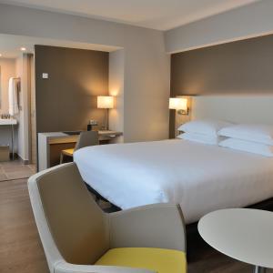 马赛AC Hotel by Marriott Marseille Prado Vélodrome的酒店客房带大型白色床和椅子