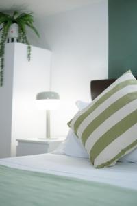 皮昂比诺Green Coast House 5的一张带绿色和白色枕头的床和一张桌子
