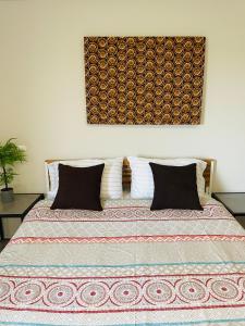 阿克拉LA SUNSET的一张带两个枕头的床和一张墙上的照片
