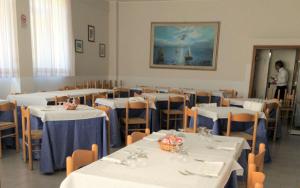 朱利亚诺瓦Hotel Holiday的一间用餐室,配有白色的桌椅,门口设有一个人