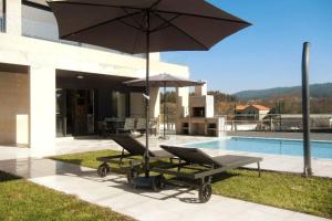 桑亨霍Chalet de diseño moderno en Sanxenxo的游泳池旁的一对椅子和一把遮阳伞
