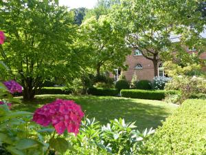 RoeulxFerme de l'Abbaye St-Feuillien的种满鲜花和树木的花园以及房屋