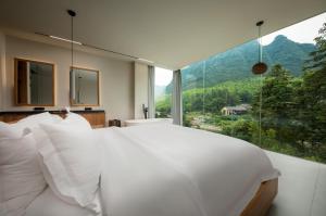 张家界张家界虚度·ANNICA旅游度假酒店的卧室设有白色的床和大窗户