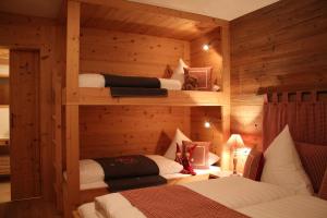 莱尔莫斯Chalet Tannenhof的木制客房内的一间卧室配有三张床