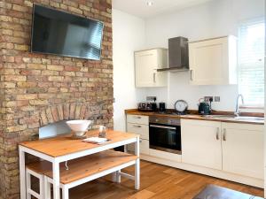 伦敦Central Location 2 bed flat, Zone II, London NW6的厨房配有白色橱柜和砖墙