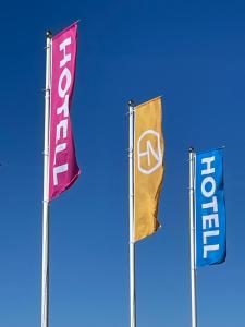 乌尔里瑟港Hotell Nyboholm的蓝天前的三面旗
