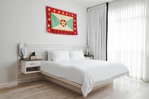 朗布兰奇简易别墅酒店的白色的卧室设有一张大床,墙上挂着国旗