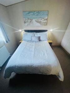 南塞尔尼Summer Breeze-Hoburne Cotswolds的卧室配有一张带白色床单和枕头的大床。