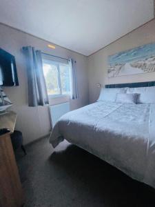 南塞尔尼Summer Breeze-Hoburne Cotswolds的一间卧室设有一张大床和一个窗户。