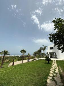 Jebel ZemzemVilla Marina Hills - Tamuda Bay的一座棕榈树和草地的白色房子