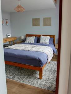 哈沃斯Farways Den的一间卧室配有一张带蓝色床单的床和一张书桌。