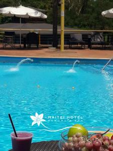 波萨达斯Hotel Maitei Posadas的游泳池旁的一张桌子和一碗水果