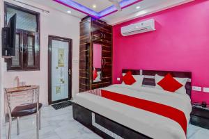 加济阿巴德Super OYO The Prima Residency的粉红色的卧室配有一张床和一张书桌