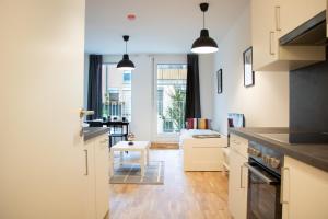 维也纳Flat2go modern apartments - Harmony of city and nature的一间带白色橱柜的厨房和一间客厅