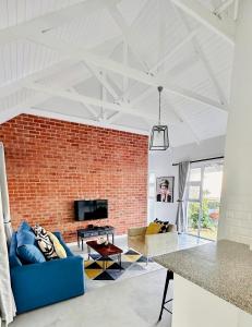 德班Stylish Loft Style Apartment的一间设有砖墙和蓝色沙发的客厅