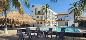 圣贝尔纳多德尔比恩托NAHIR apartamento de playa en condominio Palmar del viento的一座带游泳池和椅子的度假村和一座建筑