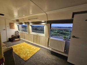 NortonMooview- the charming double decker bus的火车房间,有两个窗户,一个黄色地毯