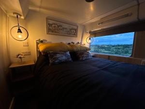 NortonMooview- the charming double decker bus的一间卧室设有一张大床和窗户
