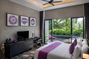 BedahuluCapung Asri Eco Luxury Resort with Private Pool Villas的一间卧室配有一张床、一张书桌和一台电视