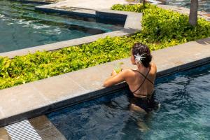 卡帕阿Sheraton Kauai Coconut Beach Resort的游泳池里的女人喝一杯