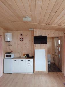 瓦多维采Zajazd Ponikiew - Noclegi Wadowice的一间厨房,配有白色家电和木制天花板