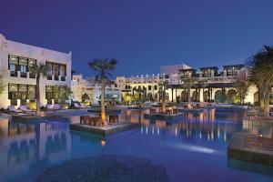 多哈Sharq Village & Spa, a Ritz-Carlton Hotel的一座棕榈树和建筑的大型游泳池
