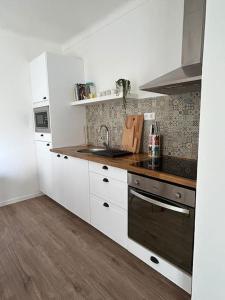 米尔芳提斯城Casa dos Avós的厨房铺有木地板,配有白色橱柜。