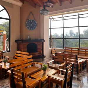 圣罗莎德卡瓦尔Hotel Casa Confort的餐厅设有木桌、椅子和墙上的时钟
