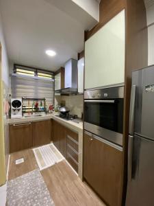 芙蓉Homestay Hana Senawang的厨房配有木制橱柜和不锈钢冰箱。