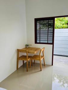Ban Noen Makokสราญรัตน์รีสอร์ท的窗户客房内的一张木桌和椅子