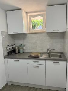 科尔丘拉MARILU的厨房配有白色橱柜、水槽和窗户。