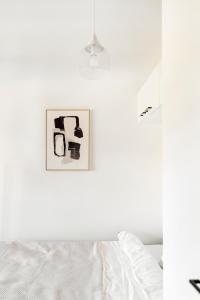 奥卢Kotimaailma Apartments Loimu VII的白色的卧室配有一张床,墙上挂着一幅画