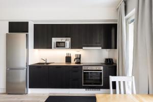 奥卢Kotimaailma Apartments Loimu VII的厨房配有黑色橱柜和不锈钢冰箱