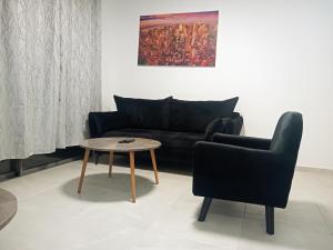 亚实基伦Agamim Park Residence的客厅配有黑色沙发和桌子