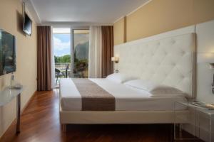 加尔达湖滨托奈利萨伏依皇宫酒店的一间带一张白色大床的卧室和一个阳台