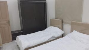 Al ‘Awālīابو عامر للشقق المفروشه的一间卧室设有两张床和黑色橱柜
