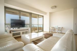 阿什杜德Luxury Apartments Blue Wave的客厅配有白色家具和平面电视