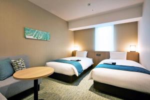 广岛广岛 穎特飯店的酒店客房带两张床、一张桌子和一张沙发