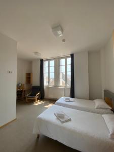 波尔多Hotel Saint Louis Beaulieu - Bordeaux的一间卧室设有两张床、一张桌子和窗户。