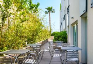戛纳B&B HOTEL Cannes La Bocca Plage的庭院里一排桌椅