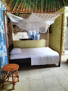 蒙巴萨Kikambala Eco Villas的一间卧室配有一张带天蓬和凳子的床