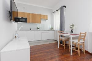 华沙City Center Aparthotel Chmielna by Renters的厨房配有白色橱柜和桌椅