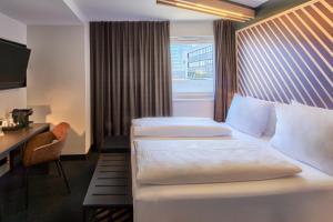 美因河畔法兰克福B&B HOTEL Frankfurt-Niederrad的酒店客房配有两张床和一张书桌