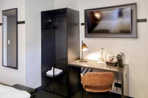 美因河畔法兰克福B&B HOTEL Frankfurt-Niederrad的客房设有书桌和墙上的电视。