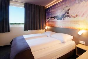美因河畔法兰克福B&B Hotel Frankfurt-Airport的卧室配有一张壁挂式海报的床