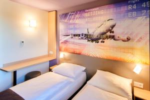 美因河畔法兰克福B&B Hotel Frankfurt-Airport的一间设有两张床的客房,墙上挂着一张海报