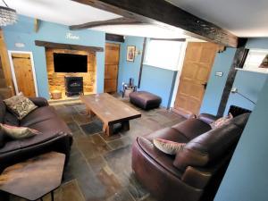 凯尼尔沃思Castle Hill Cottage on a Scheduled Monument的客厅配有皮革家具和壁炉